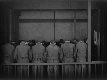 Movie still from “Metropolis” (1927), directed by Fritz Lang – A black and white photo of a group of men standing next to each other; Wide shot, Low angle