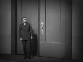 Movie still from “Metropolis” (1927), directed by Fritz Lang – A black and white photo of a man standing in front of a door; Medium shot, High angle