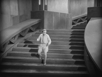 Movie still from “Metropolis” (1927), directed by Fritz Lang – A man running down a set of stairs; Wide shot, High angle