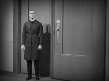 Movie still from “Metropolis” (1927), directed by Fritz Lang – A black and white photo of a man standing in front of a door; Medium shot, Low angle
