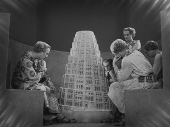 Movie still from “Metropolis” (1927), directed by Fritz Lang – A black and white photo of a group of people sitting in front of a building; Wide shot, Low angle