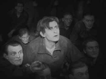 Movie still from “Metropolis” (1927), directed by Fritz Lang – A group of men sitting in a dark room; Medium shot, High angle