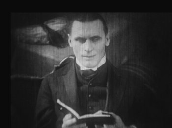 Movie still from “Metropolis” (1927), directed by Fritz Lang – A black and white photo of a man holding a notebook; Close Up shot, High angle