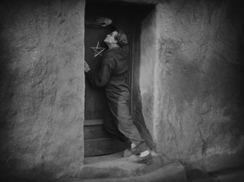 Movie still from “Metropolis” (1927), directed by Fritz Lang – A man standing in the doorway of a house; Wide shot, High angle
