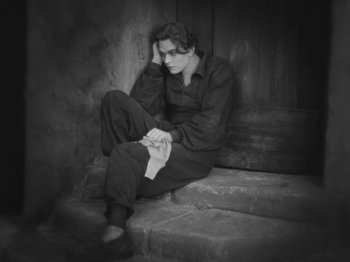 Movie still from “Metropolis” (1927), directed by Fritz Lang – Black and white photograph of a man sitting on steps; Medium shot, High angle