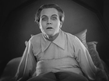 Movie still from “Metropolis” (1927), directed by Fritz Lang – An older woman sitting on a couch looking at the camera; Medium shot, Low angle