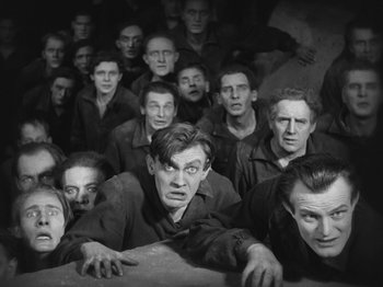 Movie still from “Metropolis” (1927), directed by Fritz Lang – A group of men in black and white photo; Medium shot, High angle