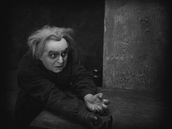 Movie still from “Metropolis” (1927), directed by Fritz Lang – An old man is leaning on a wooden table; Medium shot, High angle