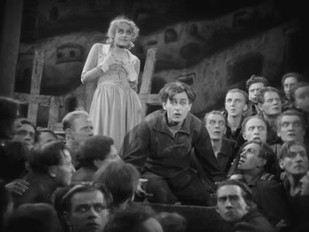 Movie still from “Metropolis” (1927), directed by Fritz Lang – A woman standing in front of a group of people; Medium shot, High angle