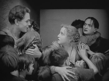 Movie still from “Metropolis” (1927), directed by Fritz Lang – A group of people gathered around each other in a room; Medium shot, High angle