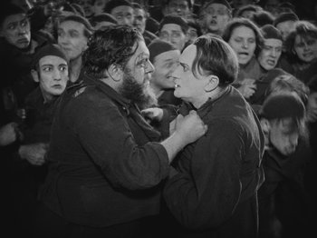 Movie still from “Metropolis” (1927), directed by Fritz Lang – A couple of people that are in a crowd of people; Medium shot, High angle