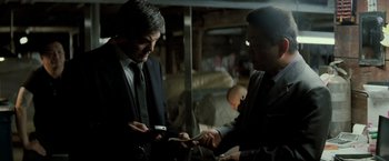 Movie still from “Michael Clayton” (2007), directed by Tony Gilroy – Two men in suits looking at their cell phones; Medium shot, Low angle