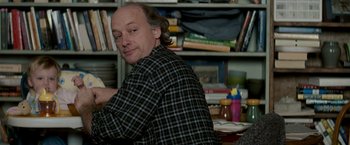 Movie still from “Michael Clayton” (2007), directed by Tony Gilroy – A man sitting at a table with a plate in front of him; Medium shot, Over the shoulder angle