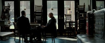 Movie still from “Michael Clayton” (2007), directed by Tony Gilroy – An older man sitting at a table in a restaurant; Wide shot, Over the shoulder angle