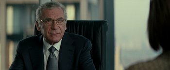 Movie still from “Michael Clayton” (2007), directed by Tony Gilroy – An older man in a suit and tie sitting in an office chair; Close Up shot, Over the shoulder angle