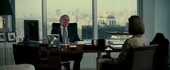 Movie still from “Michael Clayton” (2007), directed by Tony Gilroy – An older man sitting at a desk in front of a large window; Medium shot, Over the shoulder angle