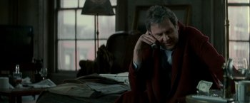Movie still from “Michael Clayton” (2007), directed by Tony Gilroy – A man sitting on a chair talking on a phone; Medium shot, Over the shoulder angle