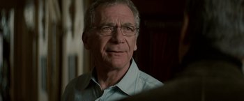 Movie still from “Michael Clayton” (2007), directed by Tony Gilroy – An older man wearing glasses looking at the camera; Close Up shot, Over the shoulder angle