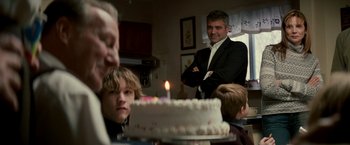 Movie still from “Michael Clayton” (2007), directed by Tony Gilroy – A group of people sitting around a cake; Medium shot, Over the shoulder angle