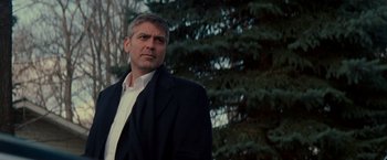 Movie still from “Michael Clayton” (2007), directed by Tony Gilroy – A man wearing a suit and tie standing next to a tree; Medium shot, Low angle