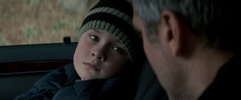 Movie still from “Michael Clayton” (2007), directed by Tony Gilroy – A boy wearing a striped hat looking at an older man; Close Up shot, Over the shoulder angle