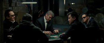 Movie still from “Michael Clayton” (2007), directed by Tony Gilroy – A man in a suit and tie playing cards; Medium shot, Over the shoulder angle