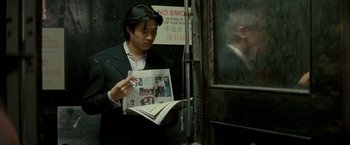 Movie still from “Michael Clayton” (2007), directed by Tony Gilroy – A man in a black suit reading a magazine; Medium shot, Over the shoulder angle