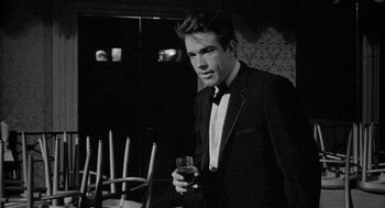 Movie still from “Mickey One” (1965), directed by Arthur Penn – A man in a tuxedo holding a glass of wine; Medium shot, Low angle