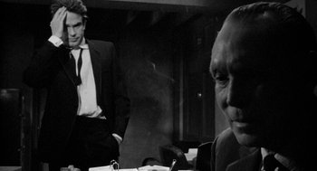 Movie still from “Mickey One” (1965), directed by Arthur Penn – A man in a suit sitting next to another man in a suit; Close Up shot, Over the shoulder angle