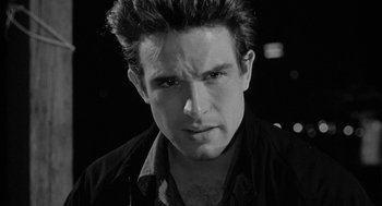 Movie still from “Mickey One” (1965), directed by Arthur Penn – Black and white photograph of a man in a black shirt; Close Up shot, Low angle