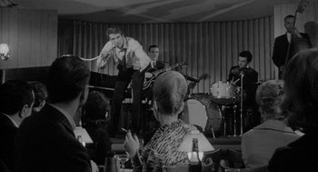 Movie still from “Mickey One” (1965), directed by Arthur Penn – A group of men and women in a room; Medium shot, Low angle