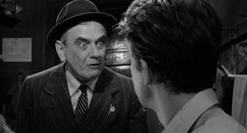 Movie still from “Mickey One” (1965), directed by Arthur Penn – An older man wearing a suit and a hat talking to a younger man; Close Up shot, Over the shoulder angle