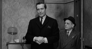 Movie still from “Mickey One” (1965), directed by Arthur Penn – A black and white photo of a man in a suit; Medium shot, Low angle