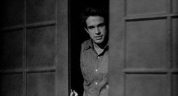 Movie still from “Mickey One” (1965), directed by Arthur Penn – Black and white photograph of a young man smoking a cigarette; Medium shot, High angle