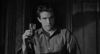 Movie still from “Mickey One” (1965), directed by Arthur Penn – A man holding a glass of wine in his right hand; Close Up shot, Over the shoulder angle