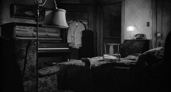 Movie still from “Mickey One” (1965), directed by Arthur Penn – A living room with a piano and a chair in it; Wide shot, High angle