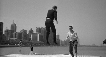 Movie still from “Mickey One” (1965), directed by Arthur Penn – A man jumping in the air while another man watches; Wide shot, Low angle