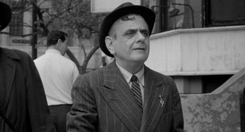 Movie still from “Mickey One” (1965), directed by Arthur Penn – An older man wearing a suit and a hat; Close Up shot, Low angle