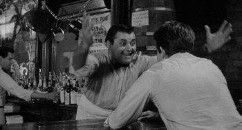 Movie still from “Mickey One” (1965), directed by Arthur Penn – Two men sitting at a bar having a good time; Medium shot, Over the shoulder angle