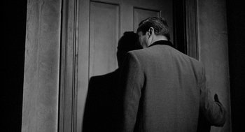 Movie still from “Mickey One” (1965), directed by Arthur Penn – A man and a woman standing next to each other in front of a door; Medium shot, Over the shoulder angle