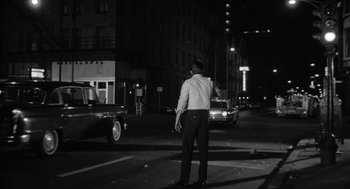 Movie still from “Mickey One” (1965), directed by Arthur Penn – A black and white photo of a man standing in the middle of the street; Wide shot, Low angle
