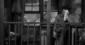 Movie still from “Mickey One” (1965), directed by Arthur Penn – A black and white photo of a man sitting on a bench; Wide shot, High angle