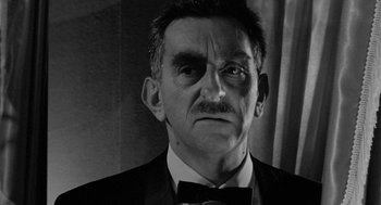 Movie still from “Mickey One” (1965), directed by Arthur Penn – An older man wearing a suit and a bow tie; Close Up shot, Low angle