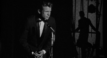 Movie still from “Mickey One” (1965), directed by Arthur Penn – A black and white photo of a man in a tuxedo; Medium shot, Low angle