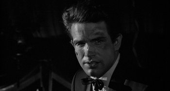 Movie still from “Mickey One” (1965), directed by Arthur Penn – Black and white photograph of a man wearing a suit and tie; Close Up shot, Over the shoulder angle