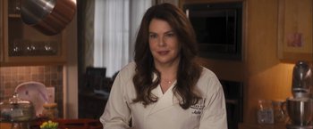A woman in a white lab coat in a kitchen