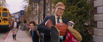 Movie still from “Middle School: The Worst Years of My Life” (2016), directed by Steve Carr – A man in a suit holding a basketball and a skateboard; Medium shot, Over the shoulder angle