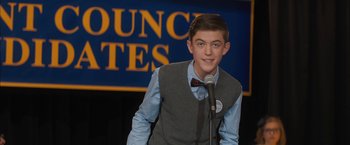 Movie still from “Middle School: The Worst Years of My Life” (2016), directed by Steve Carr – A young man standing at a podium with a microphone in his hand; Medium shot, Low angle