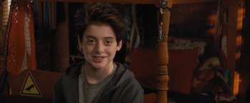 Movie still from “Middle School: The Worst Years of My Life” (2016), directed by Steve Carr – A young man smiling for the camera while sitting in a chair; Close Up shot, Over the shoulder angle