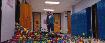 Movie still from “Middle School: The Worst Years of My Life” (2016), directed by Steve Carr – A man in a suit standing in front of a pile of balls; Wide shot, High angle